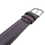 نمای نزدیک از کمربند چرم مردانه رنگ قهوه ای طرح صاف با سگک نقره ای روی پس زمینه سفید