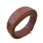 کمربند چرمی رنگ عسلی طرح کروکدیلی با سگک نقره ای که به صورت حلقوی ایستاده روی پس زمینه سفید هستش