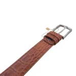 نمای نزدیک از کمربند چرم مردانه رنگ عسلی طرح کروکدیلی با سگک نقره ای روی پس زمینه سفید