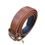 کمربند چرمی رنگ عسلی طرح فلوتر با سگک نقره ای که به صورت حلقوی ایستاده روی پس زمینه سفید هستش